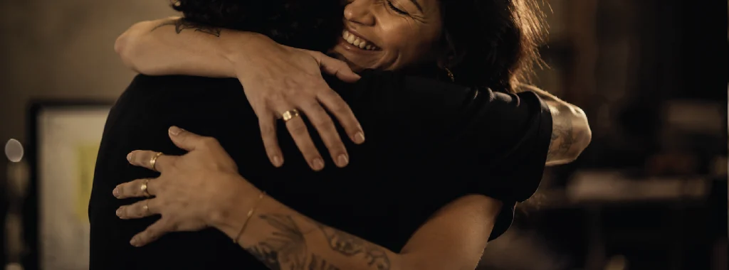 Abraço entre duas pessoas do time depois de uma entrega, sorrindo.