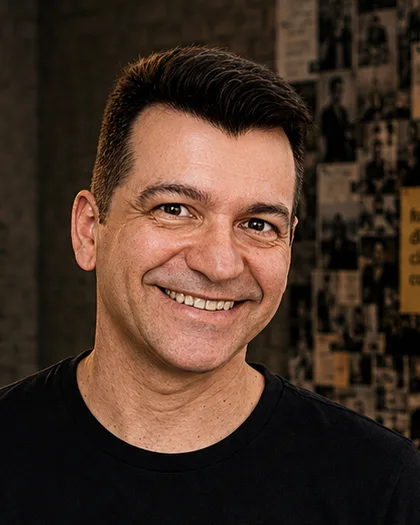 Integrante do time da Laeta sorrindo de frente, camiseta preta, parede de referências ao fundo.