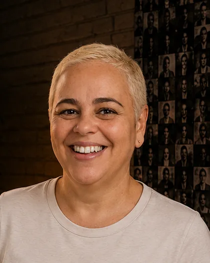 Integrante do time da Laeta de cabelo curto claro, sorriso aberto, camiseta clara, luz dourada.