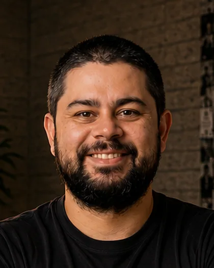 Integrante do time da Laeta de cabelo escuro despenteado e camisa preta, sorriso suave, luz quente da janela.